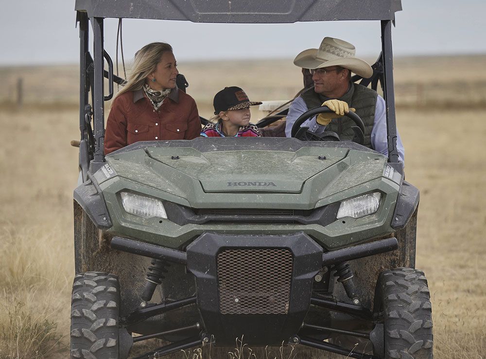 A family riding in an ATV in the pasture looking around.